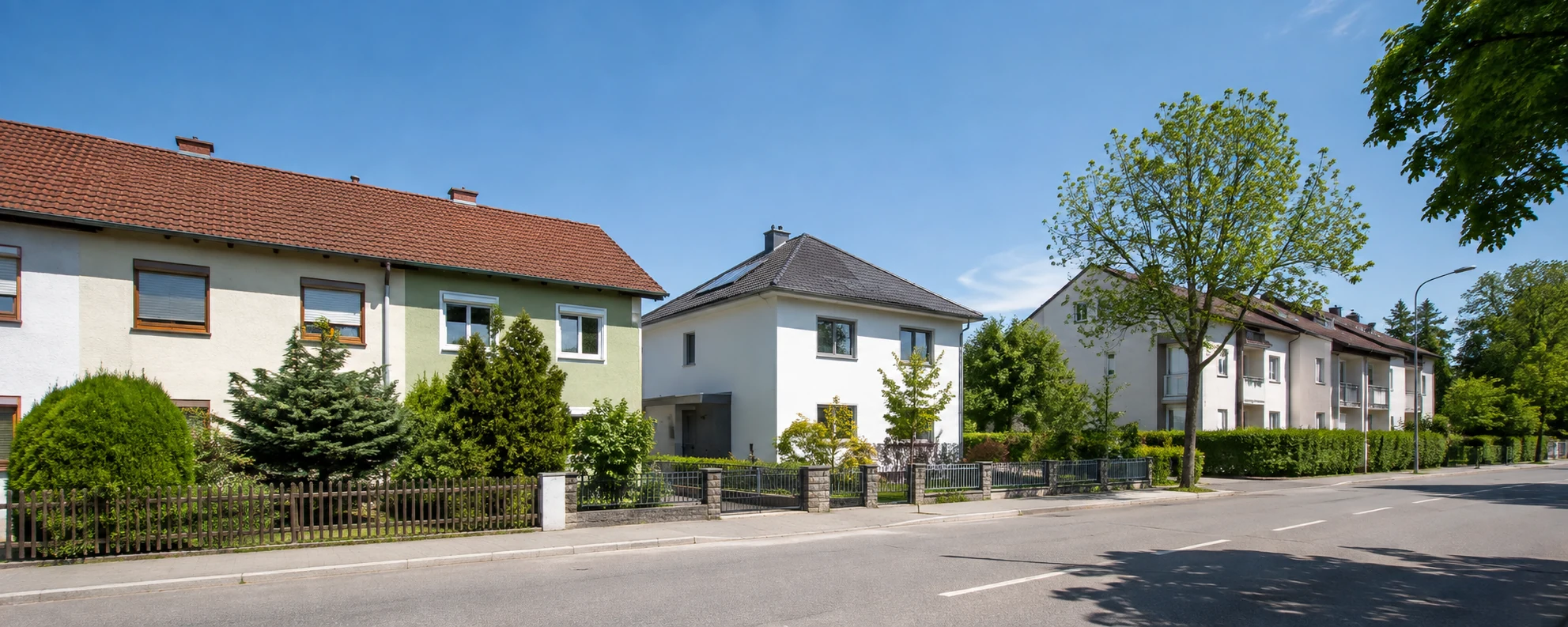 Helle Wohnstraße mit Reihenhäusern, einem Einfamilienhaus und einem kleinen Wohnhaus